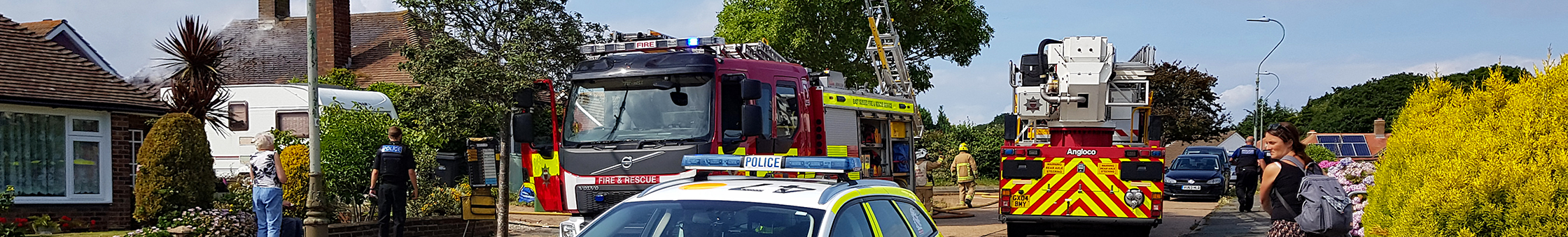 Police car and fire engines in a street of houses