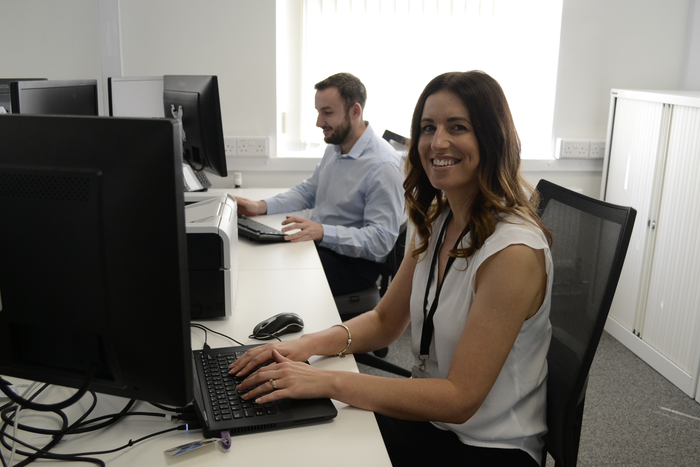 Female colleague on computer smiling and looking at camera