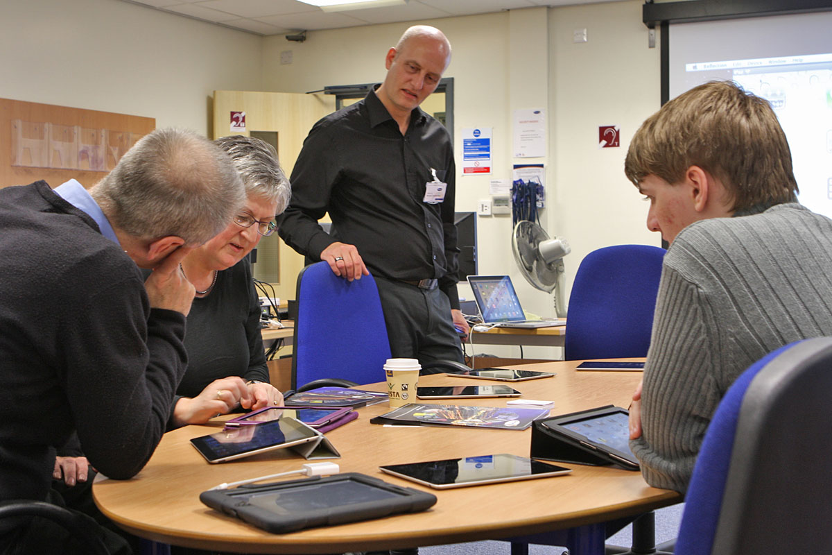 colleagues in training around an iPad on a table
