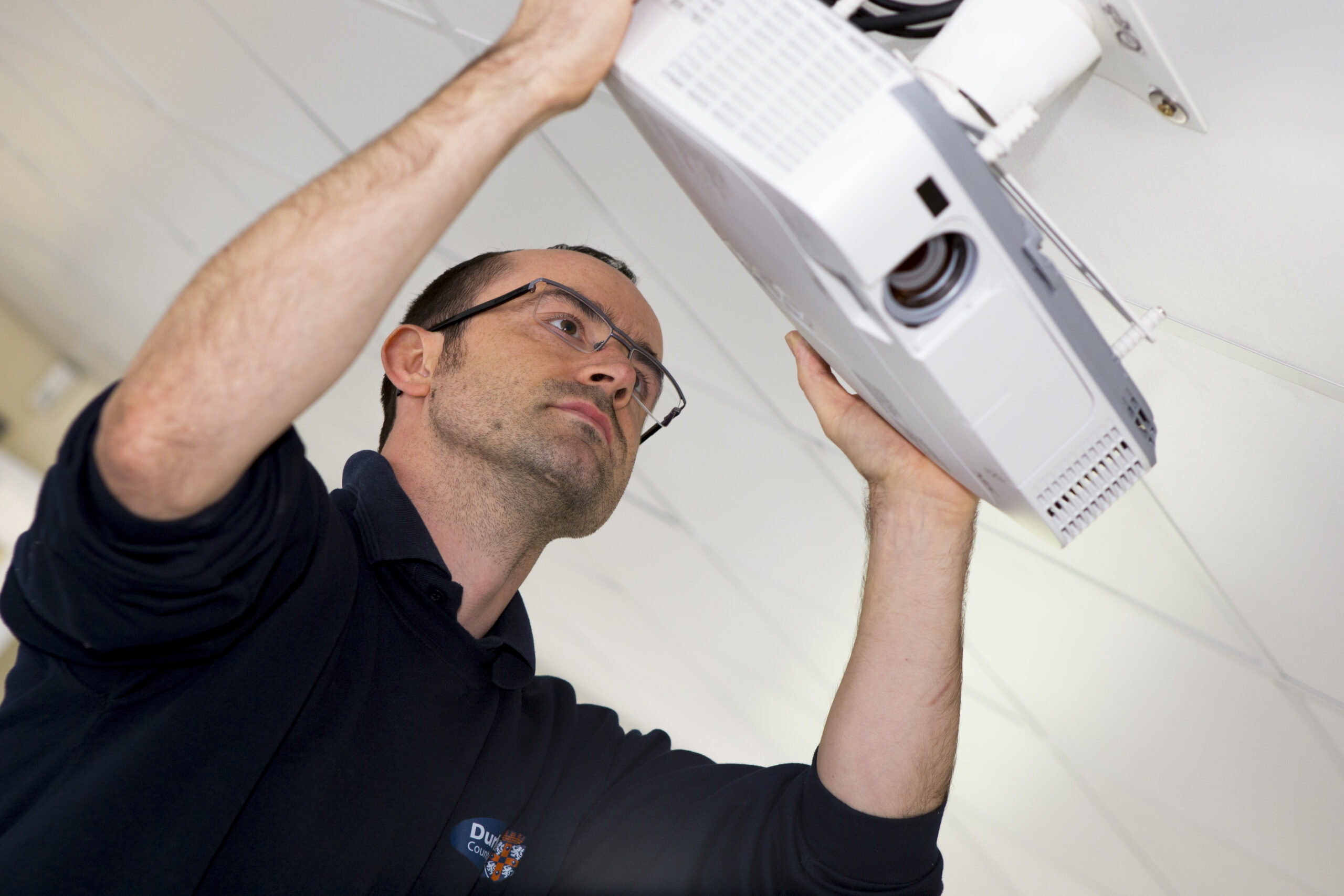 DCC employee fitting a projector