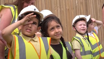 Young children in hi-vis jackets and construction helmets