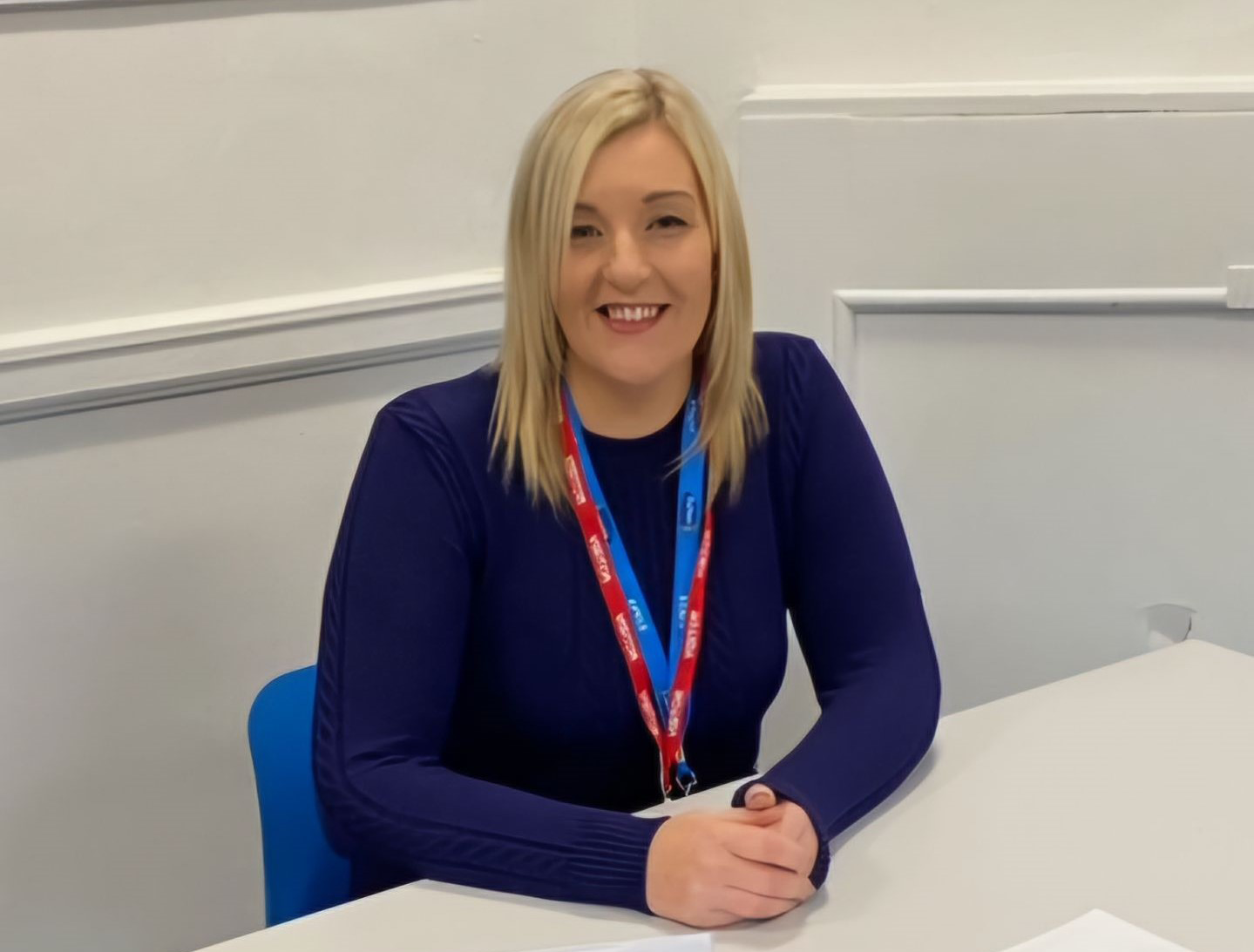 Woman sat behind a desk smiling