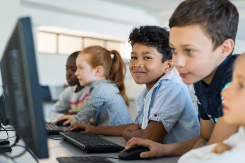 Children smiling on computers in the classroom
